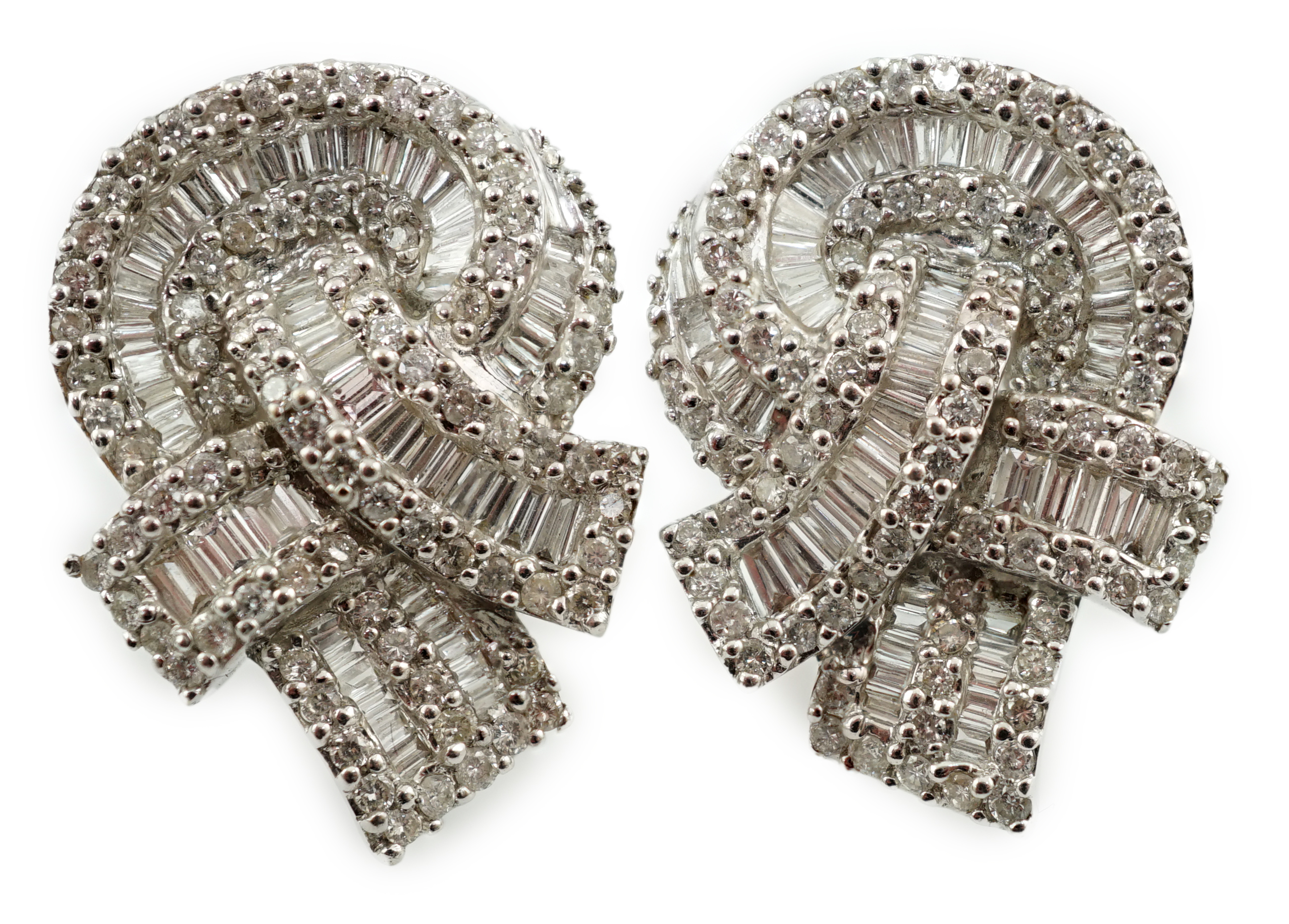 A pair of 18k white gold and pavé set round and baguette cut diamond cluster set 'knot' earrings